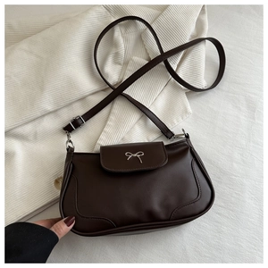 Close-up of a vintage dark brown shoulder bag featuring a silver bow metal buckle