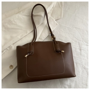 Detail of brown tote bag featuring contrast white stitching and large front pocket