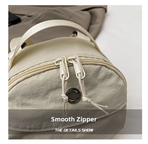 Close-up of smooth dual zippers and nylon texture on the beige round crossbody bag