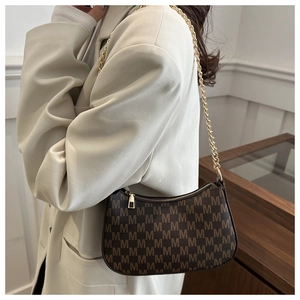 Detail shot of vintage brown crescent bag with M-pattern print and gold chain strap