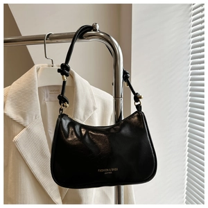 Close-up of black glossy leather handbag featuring a stylish knotted shoulder strap detail