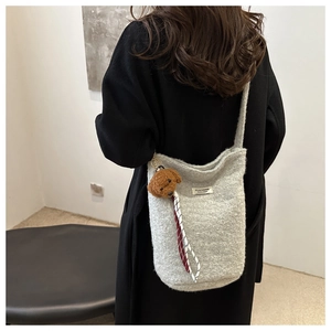 Winter wool bucket bag in grey with plush dog charm and woven strap, side view on model