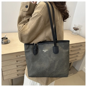 Shoulder shot of large grey-green tote bag with gold lettering and black straps
