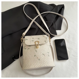Détail du sac seau en paille avec broderie florale et boucle en métal doré