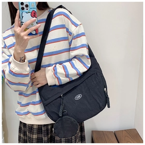Detail of black nylon crossbody bag featuring a round coin pouch and logo plaque