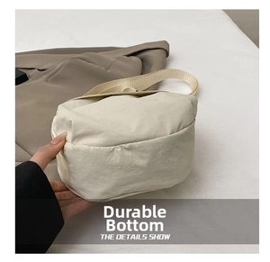 Close-up of the wear-resistant reinforced bottom of this cream fabric crossbody bag