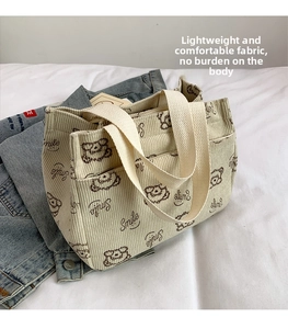 Dettaglio di una borsa tote in velluto a coste beige con stampa orso e tasca frontale