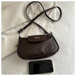 Detail view of a brown baguette bag featuring a silver bow buckle and adjustable strap