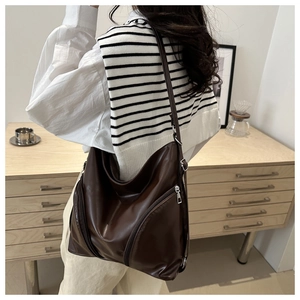 Detail of a dark brown matte leather bag with adjustable strap and side zipper pocket