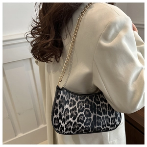Detail of leopard print underarm bag featuring a gold chain strap and moon-shaped design