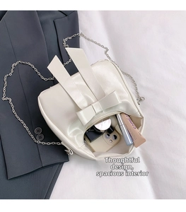 Detailed interior of white bow shoulder bag showing storage for phone and cosmetics