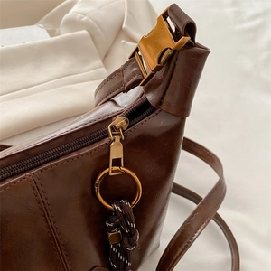 Retro dark brown crossbody dumpling bag with golden metal clasp and woven cord detail