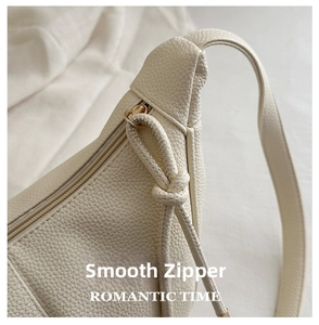 Detailed macro shot of smooth metal zipper and leather knot on cream dumpling bag
