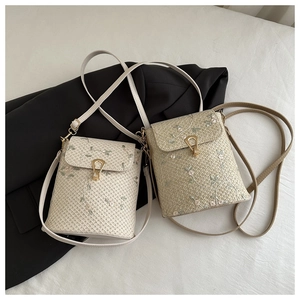 Detailed view of floral embroidery and gold metal clasp on woven crossbody bags