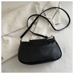 Close-up of black crossbody bag with adjustable strap and silver buckle on white fabric