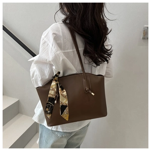 Close-up of brown leather tote bag with vintage printed silk scarf on shoulder strap