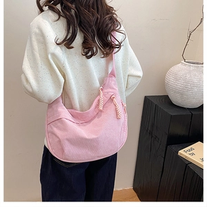 Detail of pink corduroy crescent bag with woven zipper pull on minimalist background