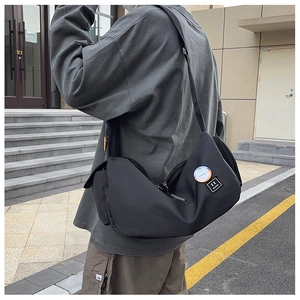 Nylon messenger bag featuring round TREND badge and adjustable strap in urban street setting