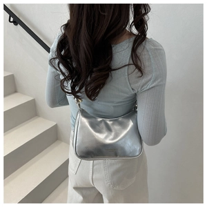 Silver baguette bag detail showing glossy leather finish and side metal buckle