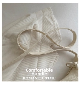 Detailed macro view of litchi-textured leather strap and knotted detail on beige bag