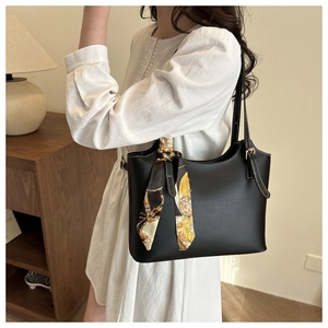 Detail of black leather tote bag with white stitching and stylish printed silk scarf