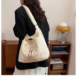 Detail of off-white corduroy tote bag with plush puppy decor and wide canvas strap