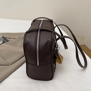 Large dark brown leather tote bag with silver zipper and charm on white surface