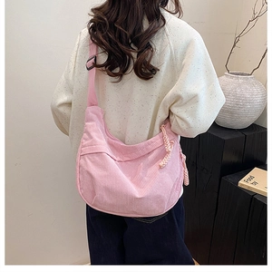Detail of pink corduroy shoulder bag showing fine texture and woven rope zipper pull
