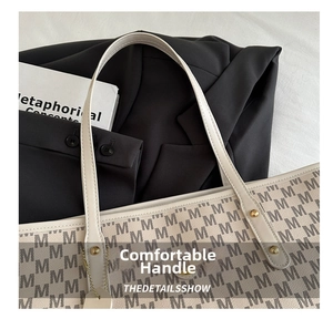 Detail of cream tote bag featuring grey M pattern and comfortable handle design