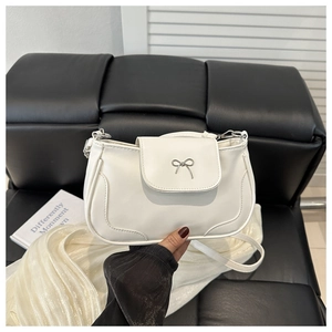 Close-up of a white PU leather shoulder bag featuring a silver metal bow detail
