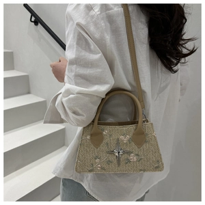 Close-up of woven beige straw handbag with floral embroidery and star metal clasp