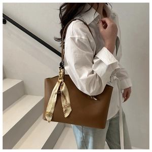 Dettaglio di una borsa tote in pelle marrone con foulard in seta vintage sulla tracolla
