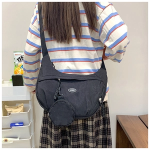 Rear view of a black nylon crescent crossbody bag with a round coin purse and logo detail