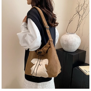 Detailed view of brown corduroy shoulder bag featuring a cute white plush dog patch