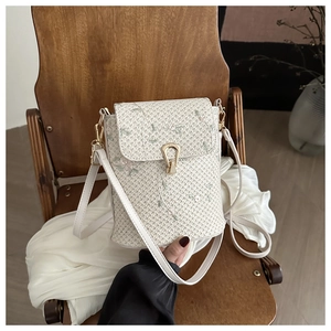 Detail of floral embroidery and gold clasp on a beige woven straw bucket bag