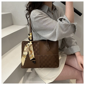 Dettaglio della borsa tote in pelle marrone scuro con texture a scacchi e foulard di seta