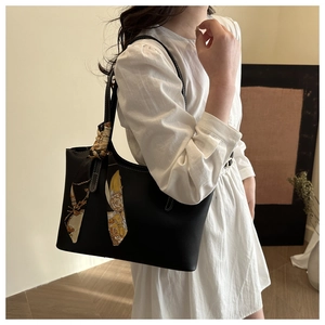 Detail of black leather tote bag with stylish patterned silk scarf on handle