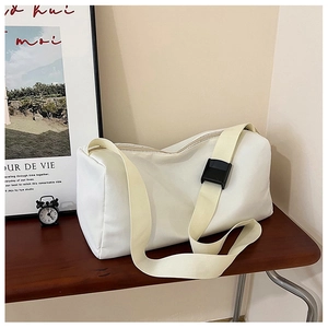 Détail du sac messager en nylon crème avec bandoulière réglable sur table en bois