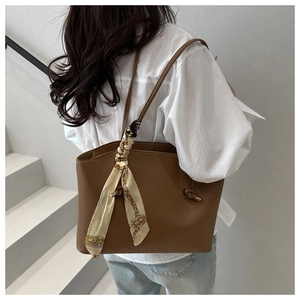 Brown leather tote bag with decorative vintage silk scarf shown on a model