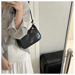 Mirror selfie showing a black glossy hobo bag with gold hardware and fashion text
