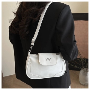 Détail d'un sac sous les aisselles blanc minimaliste avec boucle noeud argenté sur blazer noir