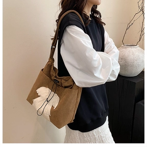 Detail of brown corduroy tote bag with cute white plush bear patch and drawstring closure