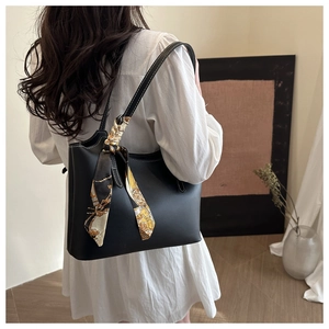 Detail of black faux leather tote bag with white contrast stitching and silk scarf accessory