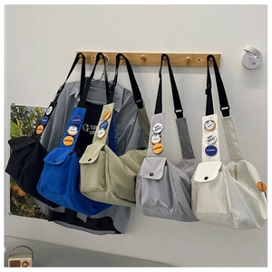 Detail of nylon messenger bags with colorful badges and front flap pockets on a rack