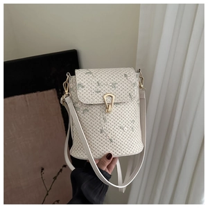 Detail of straw woven bucket bag with green floral embroidery and golden horseshoe buckle