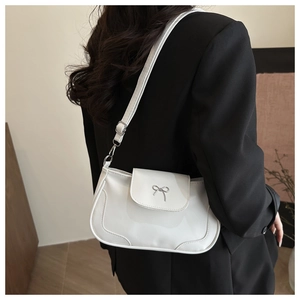 Close-up of a white leather shoulder bag featuring a silver metal bow buckle on a model