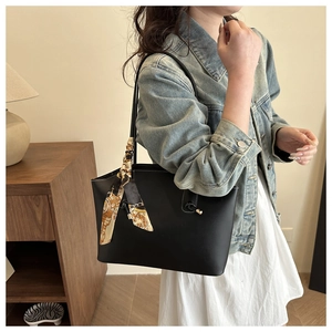 Dettaglio della borsa tote in pelle nera con elegante foulard di seta sul manico
