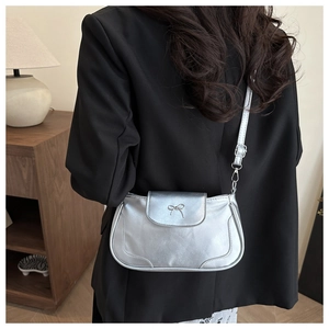 Detail view of silver bow-knot buckle on metallic PU leather underarm bag for women