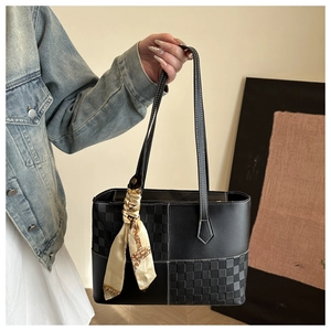 Detail of black woven checkerboard tote bag with elegant scarf accent and leather texture