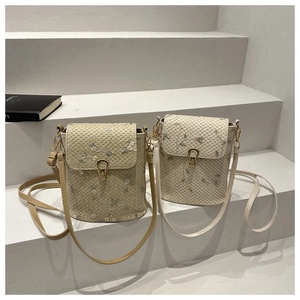 Détail de broderie florale sur sacs seaux tissés avec boucles dorées vintage